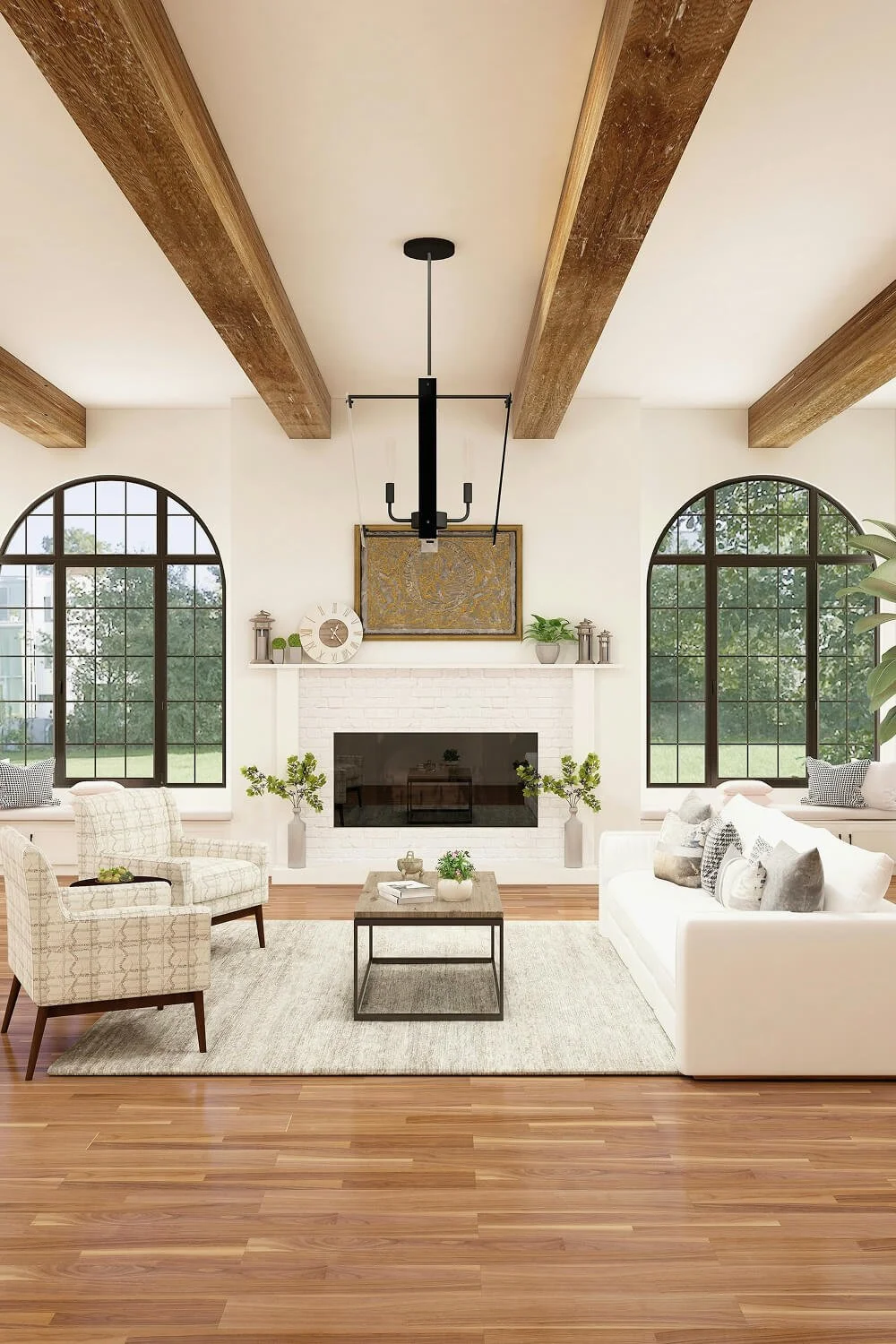 Living room with white walls, large arched windows, a white brick fireplace, beige armchair, white sofa with patterned pillows, wooden coffee table, and decorative plants, ceiling with exposed wooden beams, and a modern black chandelier.