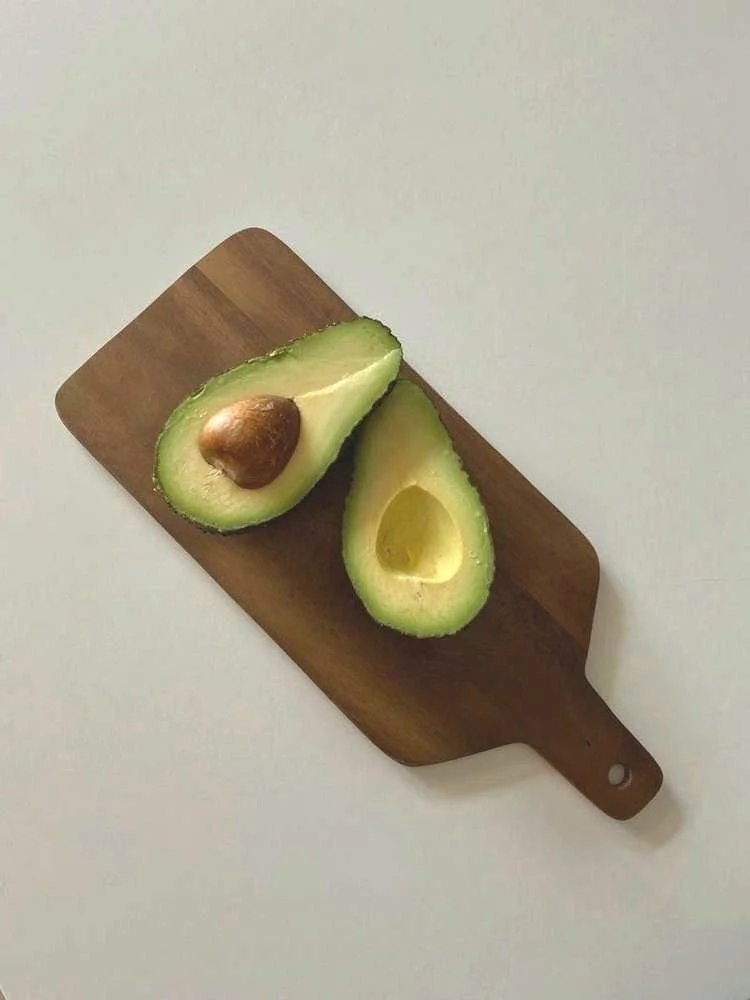 Een snede avocado met een bruine pit op een houten snijplank.