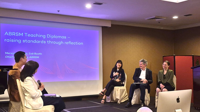 Panel discussion at a conference with a presentation slide titled 'ABRSM Teaching Diplomas - raising standards through reflection' and four participants, including two women and two men, seated on stage.
