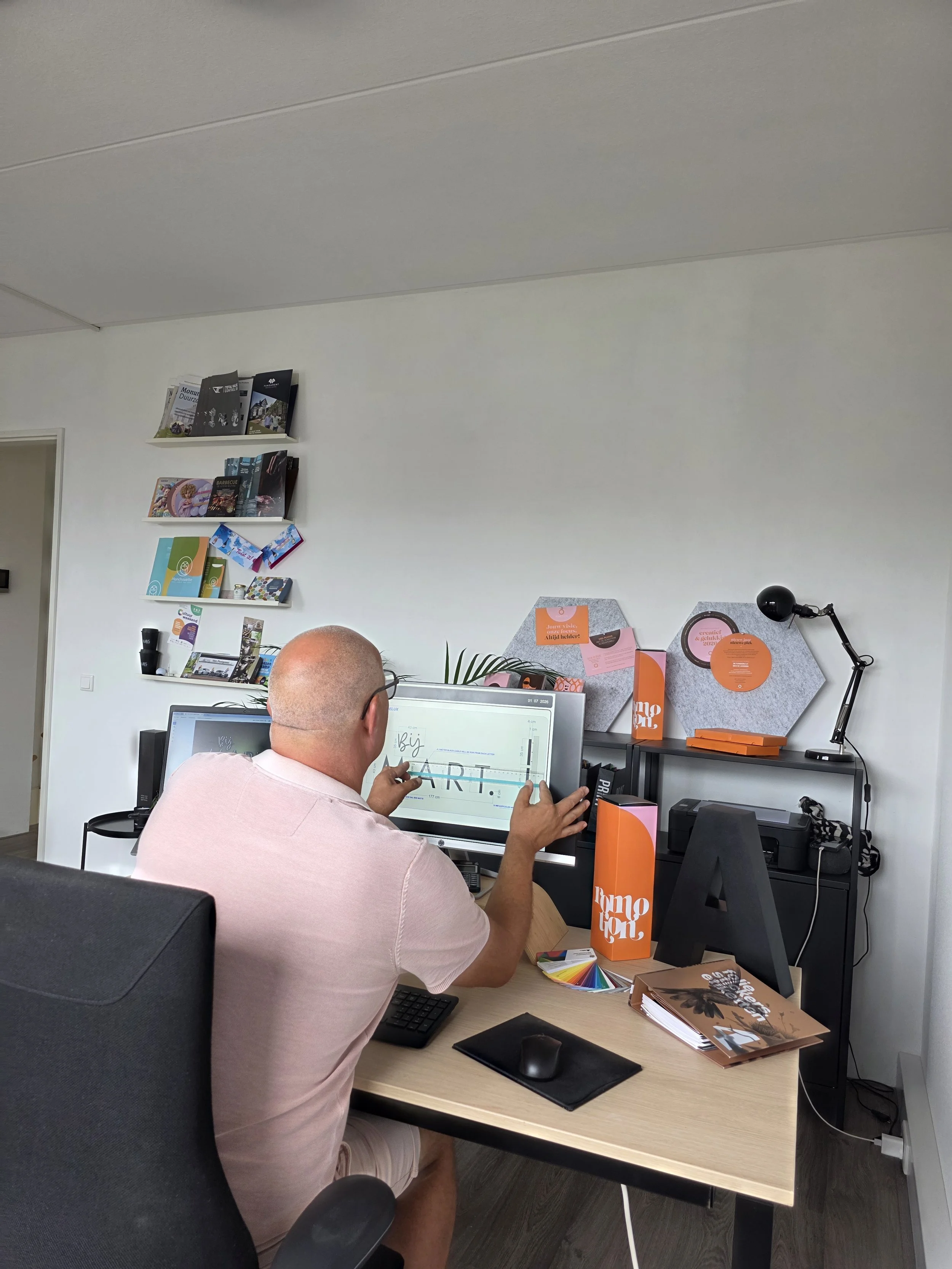 Man zit aan een bureau in een kantoor, gebruikt een touchscreen monitor om te ontwerpen of te tekenen.