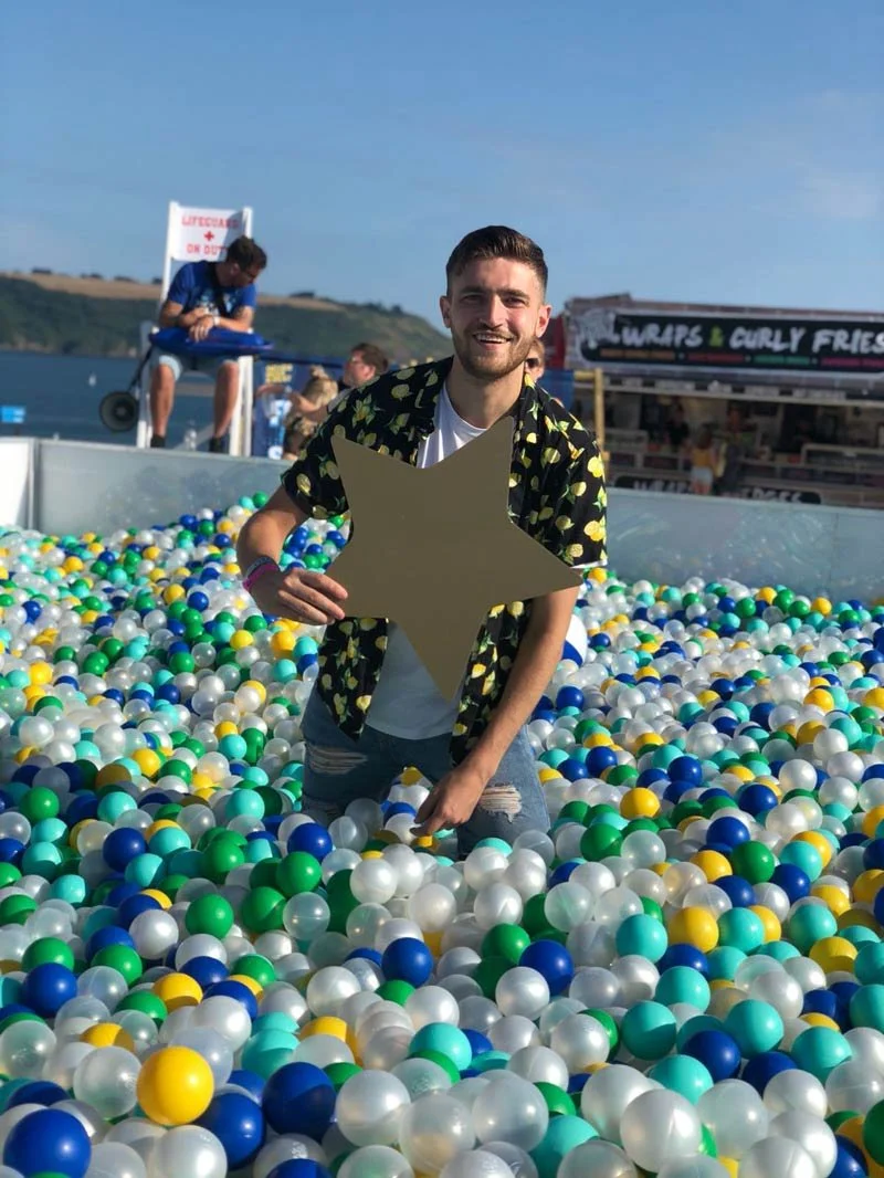 Man standing in a green, blue and white ball pit at an outdoor brand activation
