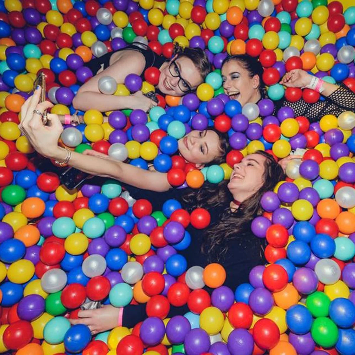 Overhead view of friends lying together in a bright multicoloured ball pit