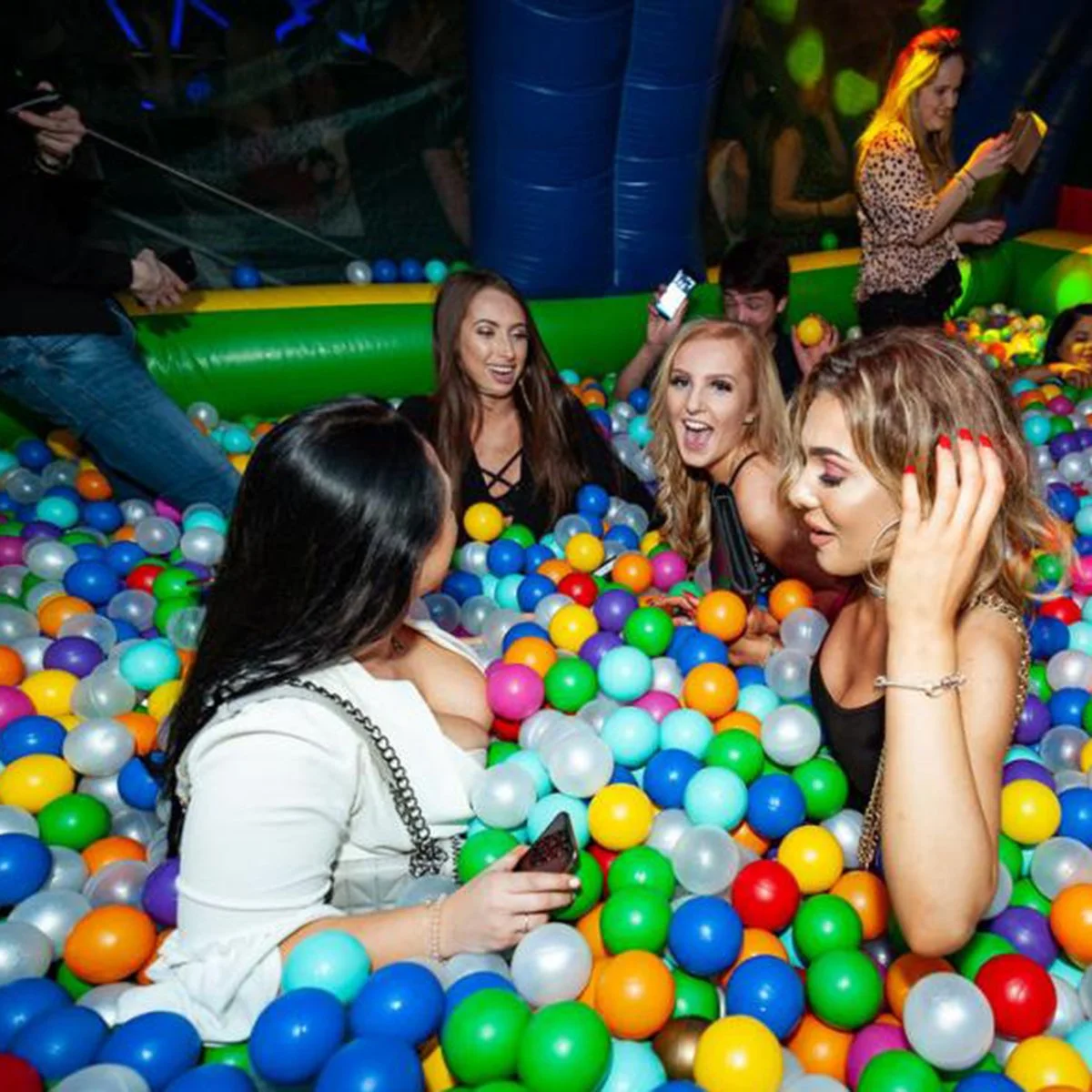 Group of friends sitting and chatting together in a large multicoloured ball pit