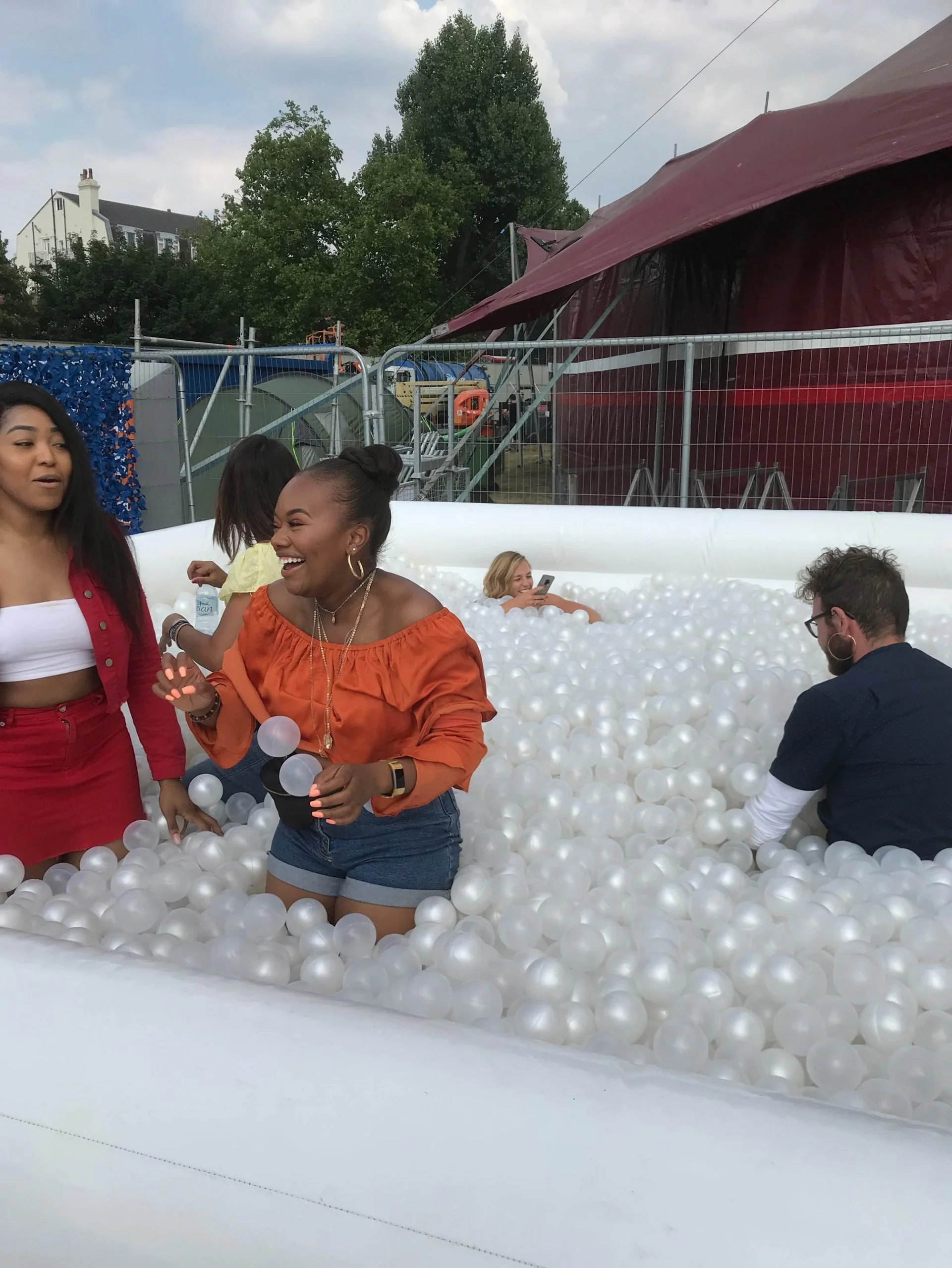 Friends standing in a white pearl ball pit at an outdoor summer event