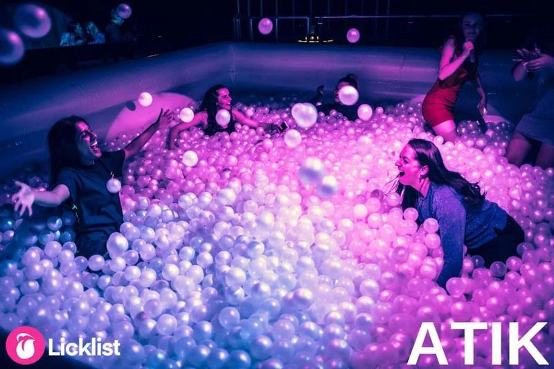 Guests lying in a ball pit under purple lighting on a nightclub dancefloor