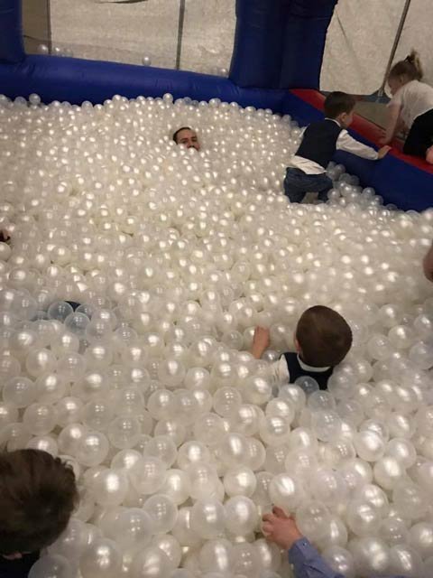 Children playing in a white pearl ball pit inside a blue inflatable enclosure