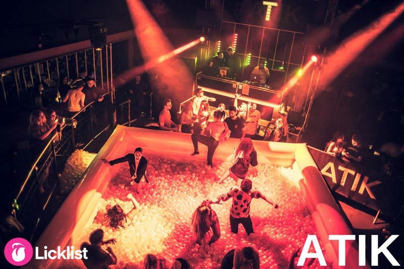 A large ball pit installed on a nightclub dancefloor under orange stage lighting