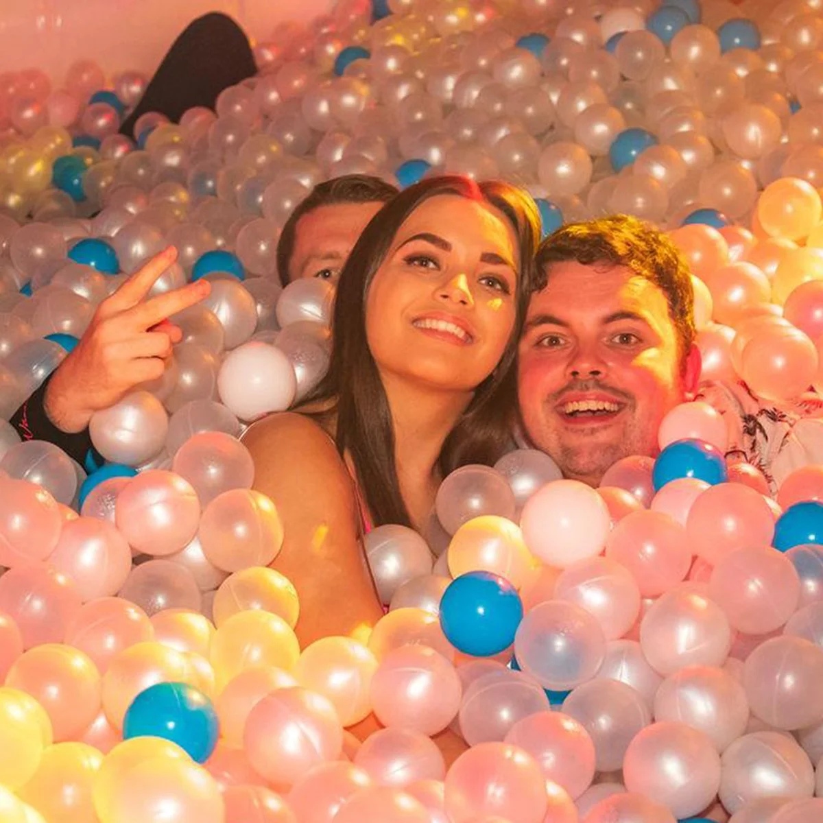 Couple smiling together among pastel pink, white and blue ball pit balls
