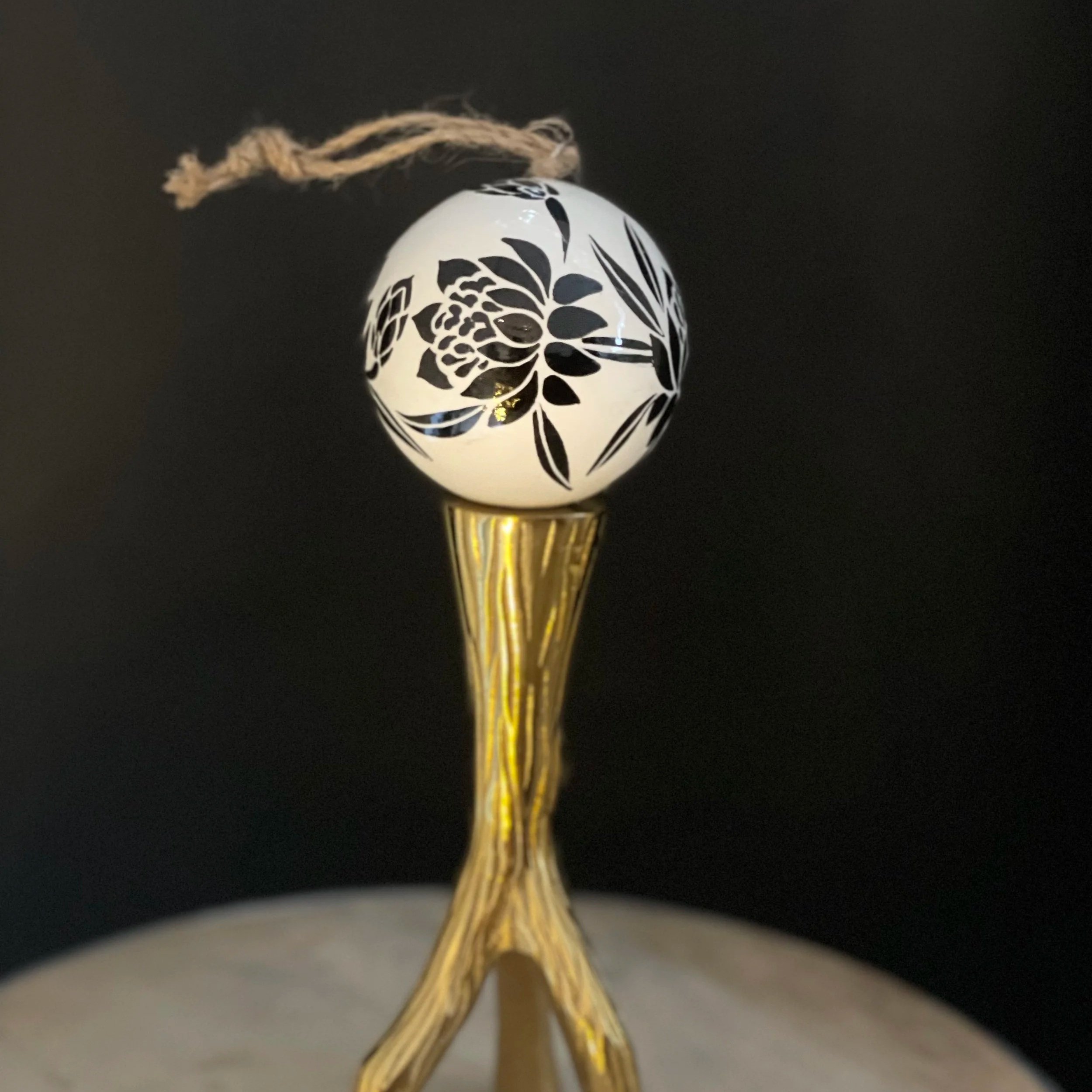 Waratah Bauble sitting on a gold candle stand, against a black background