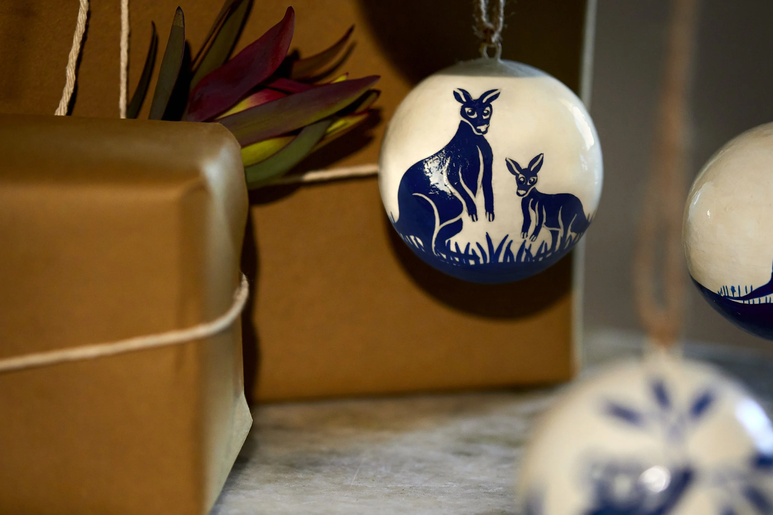 Hand-painted kangaroo bauble hanging against a dark, moody background