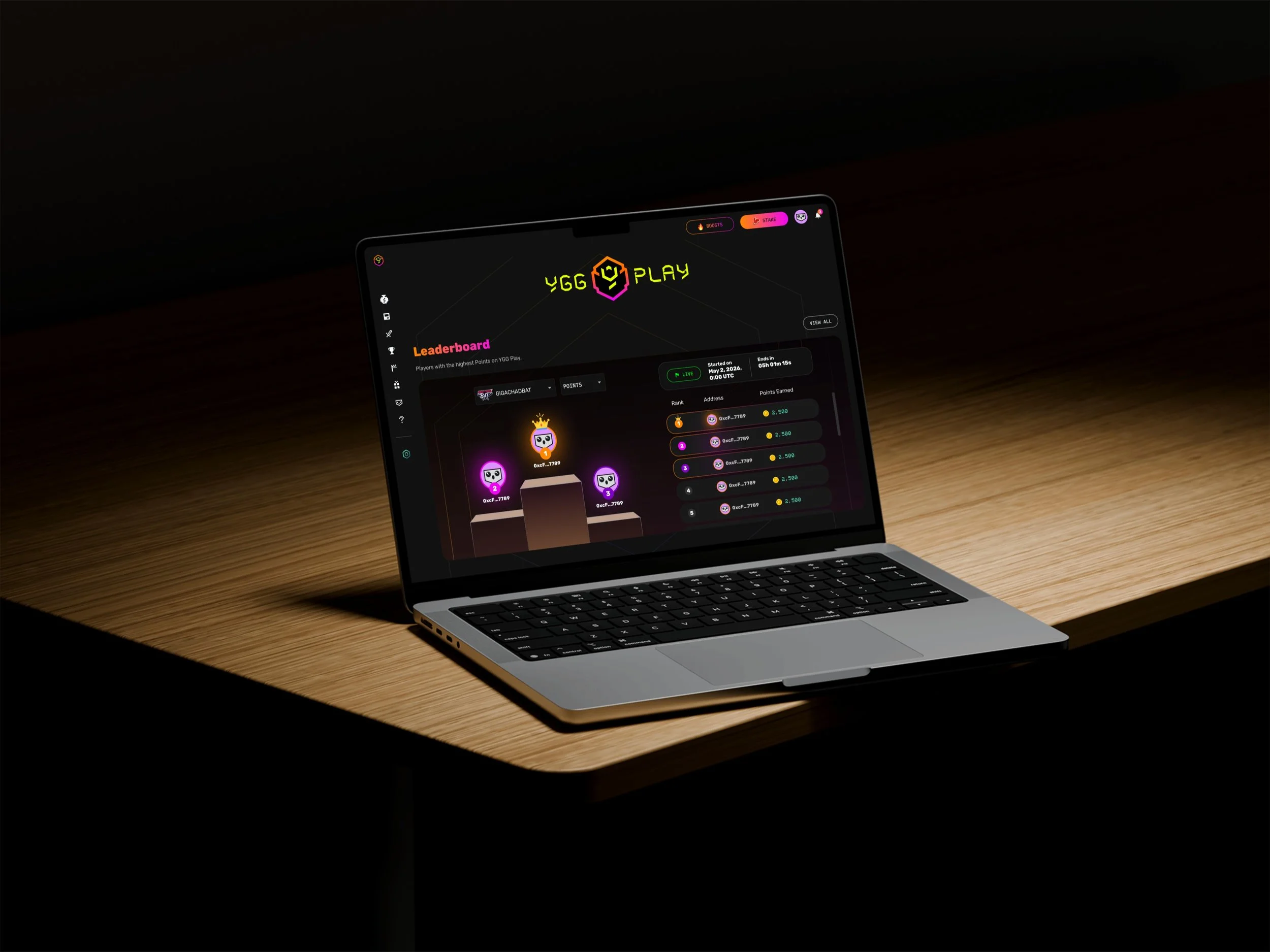 A laptop on a wooden desk displaying a gaming website called YGG Play, with leaderboard and character icons.