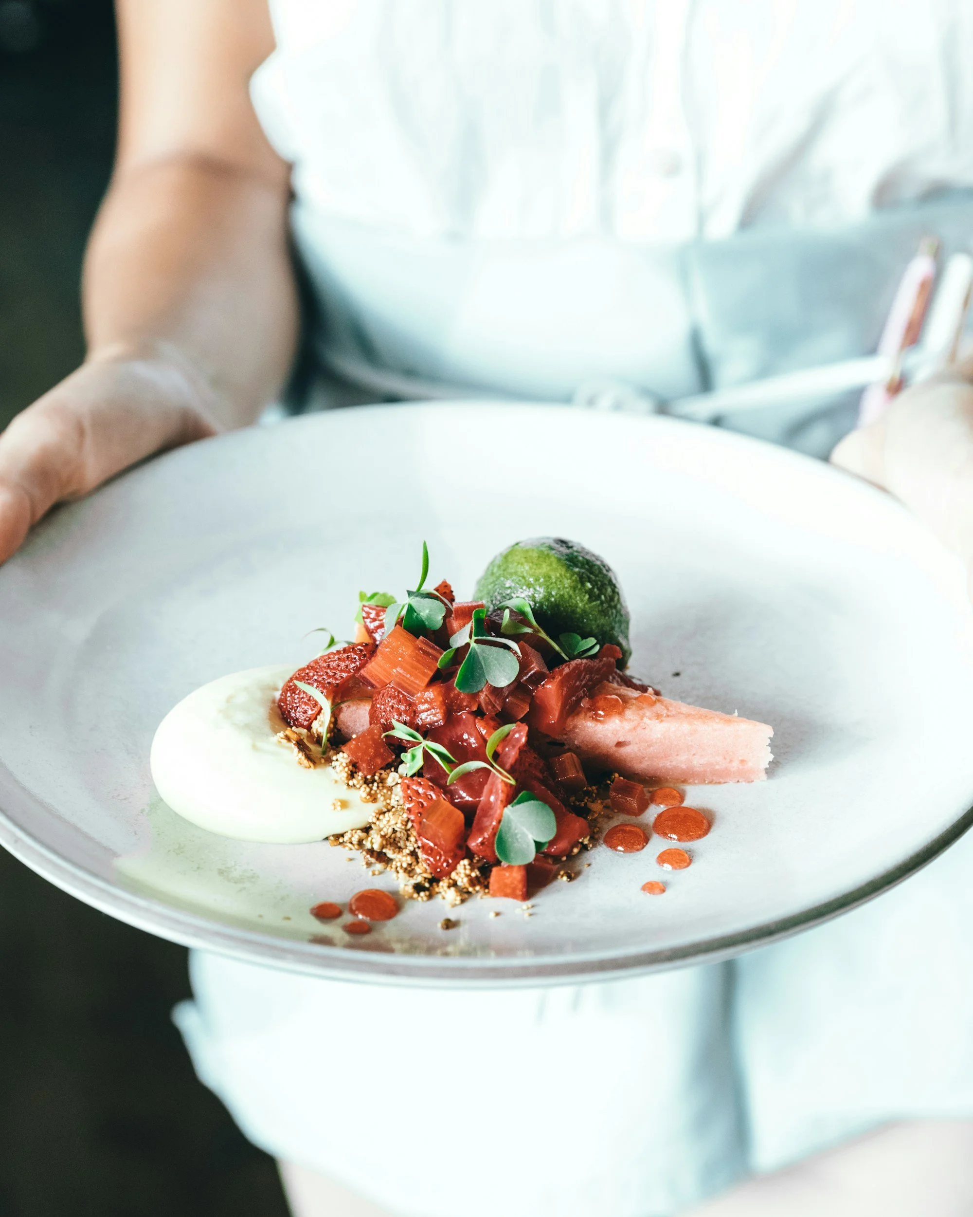 Gourmet assiette avec un dessert décoré de fruits, micro-pousses et sauces, vue rapprochée
