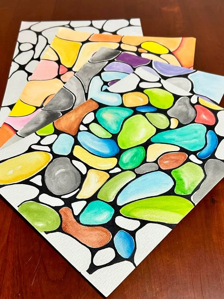 Colorful abstract paintings of stones or pebbles on white background on a table.