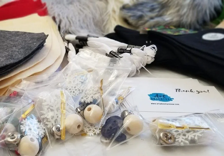 Various holiday-themed craft supplies including snowflake cutouts, bells, and beads, along with a thank you card on a table.