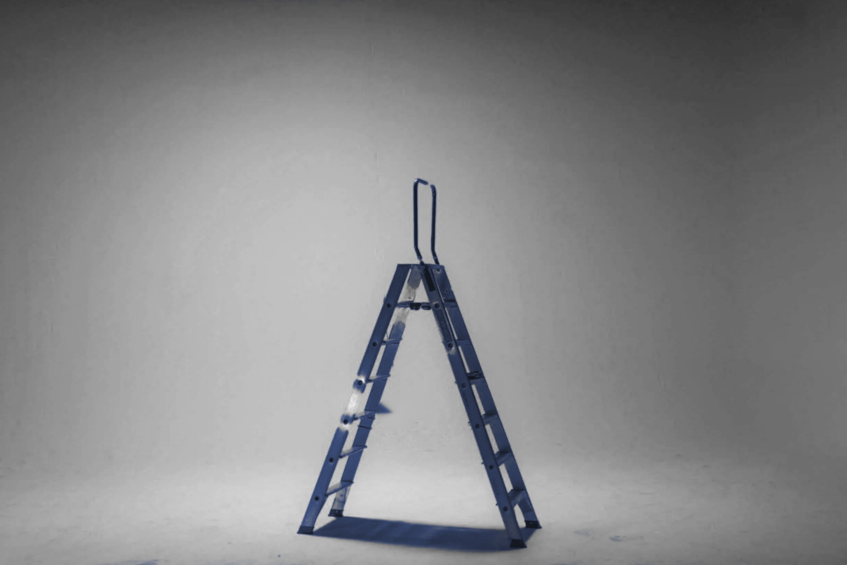 A blue ladder sitting in the middle of an empty studio.