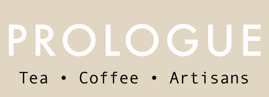 A beige sign with the word 'PROLOGUE' in large white letters and the words 'Tea, Coffee, Artisans' in smaller black letters below, separated by dots.