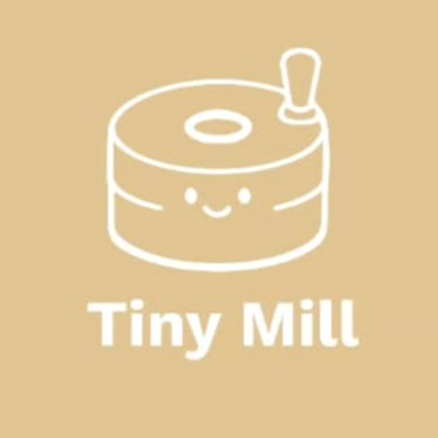A cute, smiling cartoon illustration of a small, round mill with a handle, along with the text 'Tiny Mill' beneath it, on a beige background.