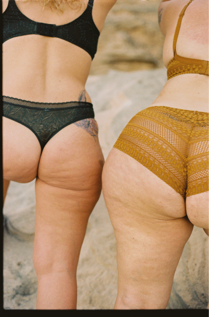 Dos mujeres en trajes de baño de encaje viendo hacia la playa.