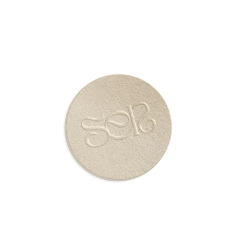 Una pastilla redonda de color beige con las letras grabadas 'sér' en relieve.