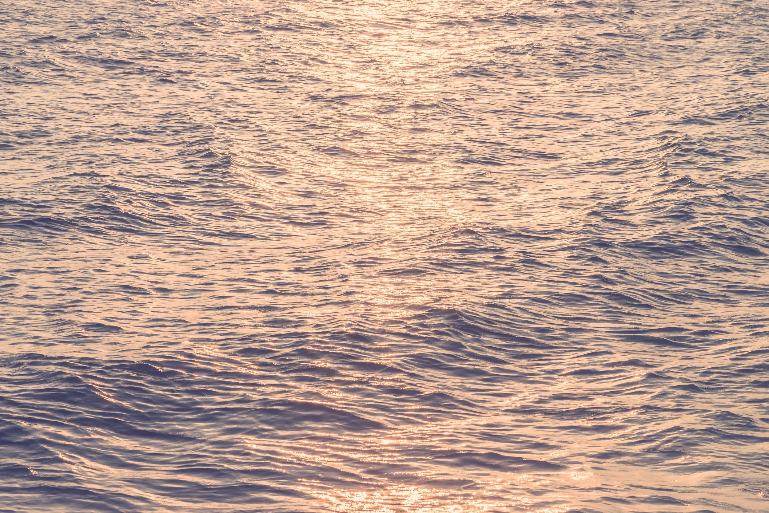 Mar en calma con reflejos dorados del sol en la superficie del agua.