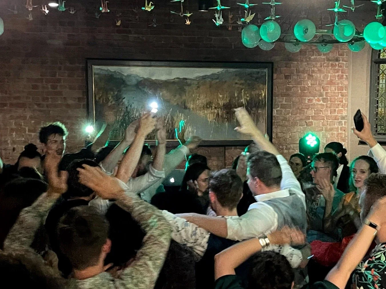 Wedding guests dancing under event lighting
