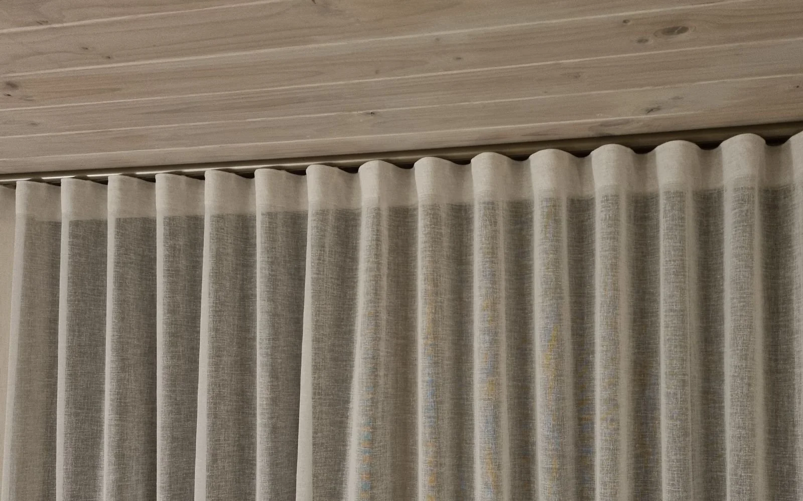 Beige curtains and cusotm hardware hanging in front of a wooden ceiling.