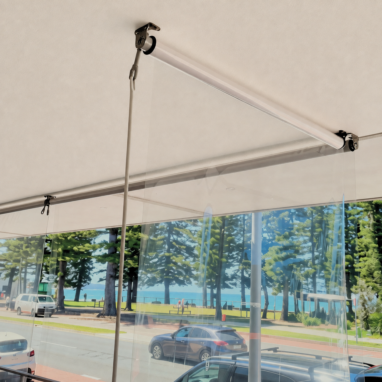 Ceiling with a projection screen and a clear plastic curtain, overlooking a parking lot, trees, and water in the background.