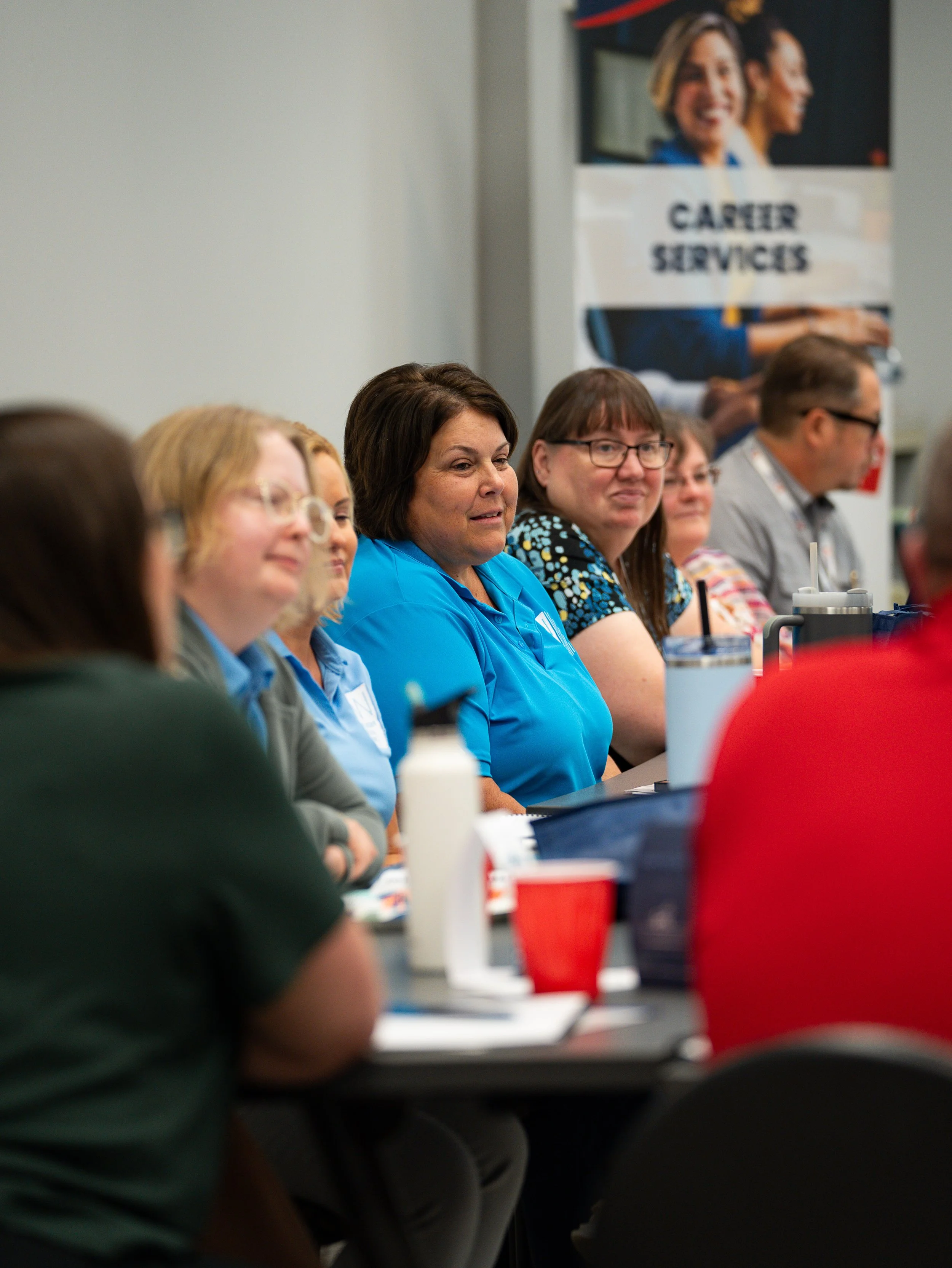 Women sitting at a table in a conference room, with a banner in the background that says "CARTER SERVICES" and features images of smiling women.