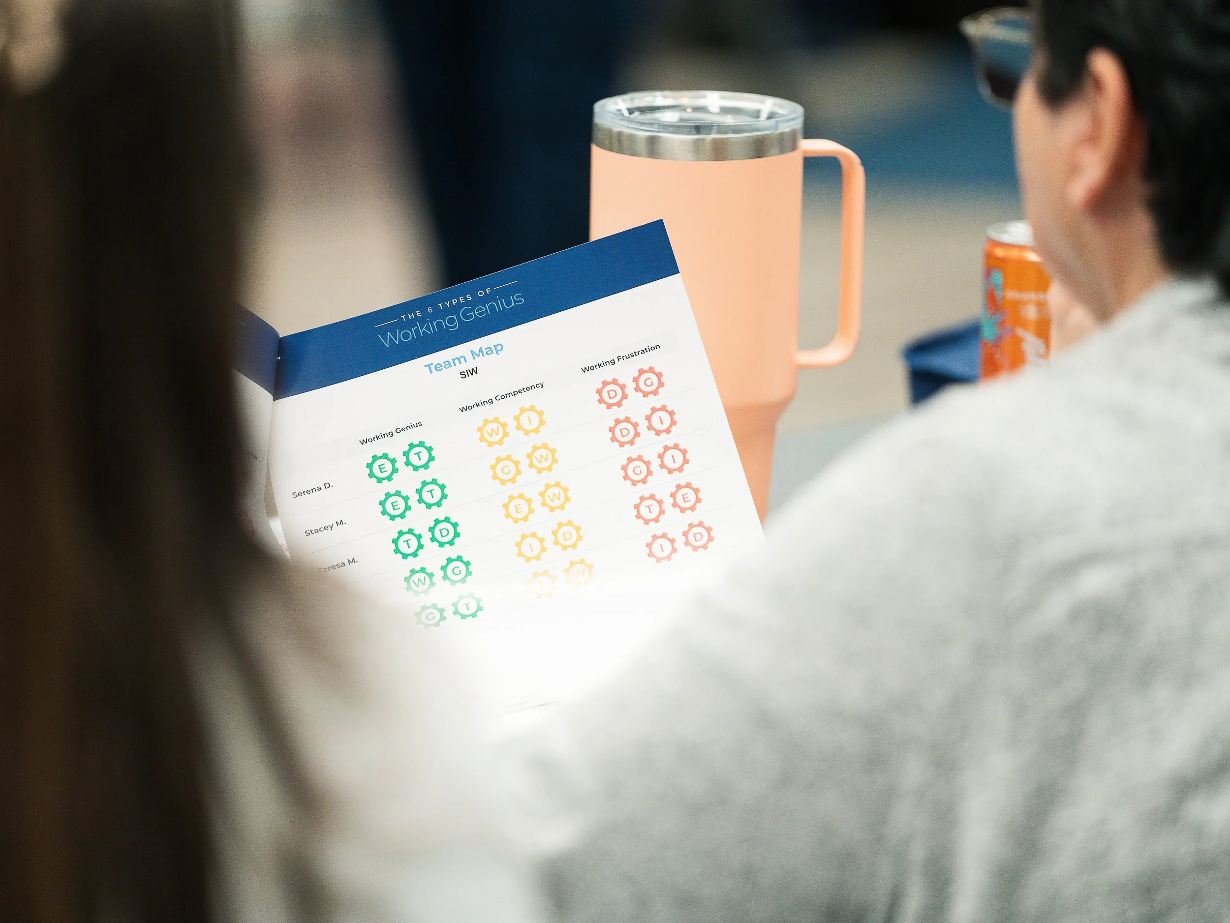 A person holding a conference or team map with colorful gear icons representing different working competencies.