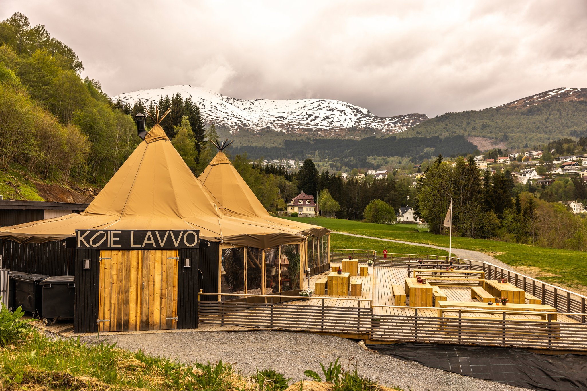 Telt på utendørsområde med fjell og hus i bakgrunnen.
