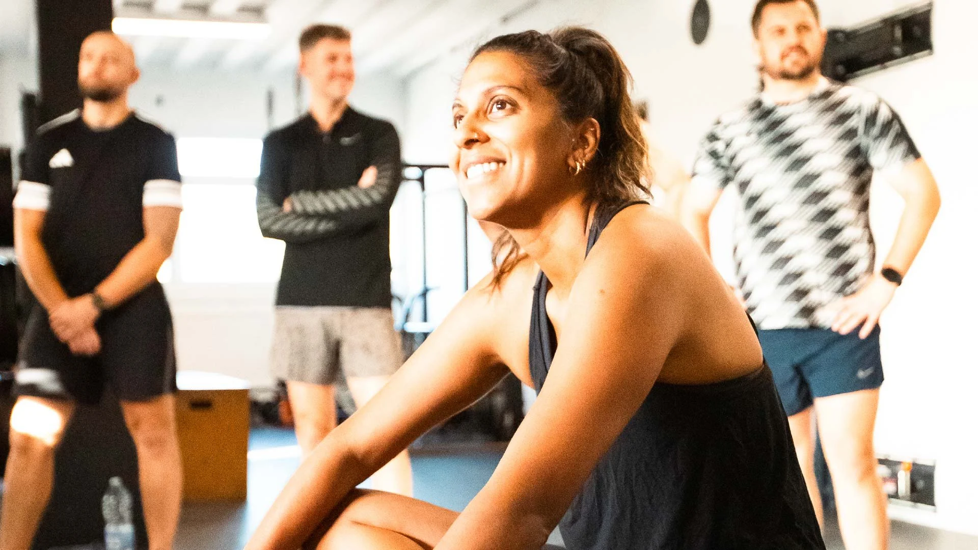 BUILT Training member smiling during a break in class, fellow members in the background