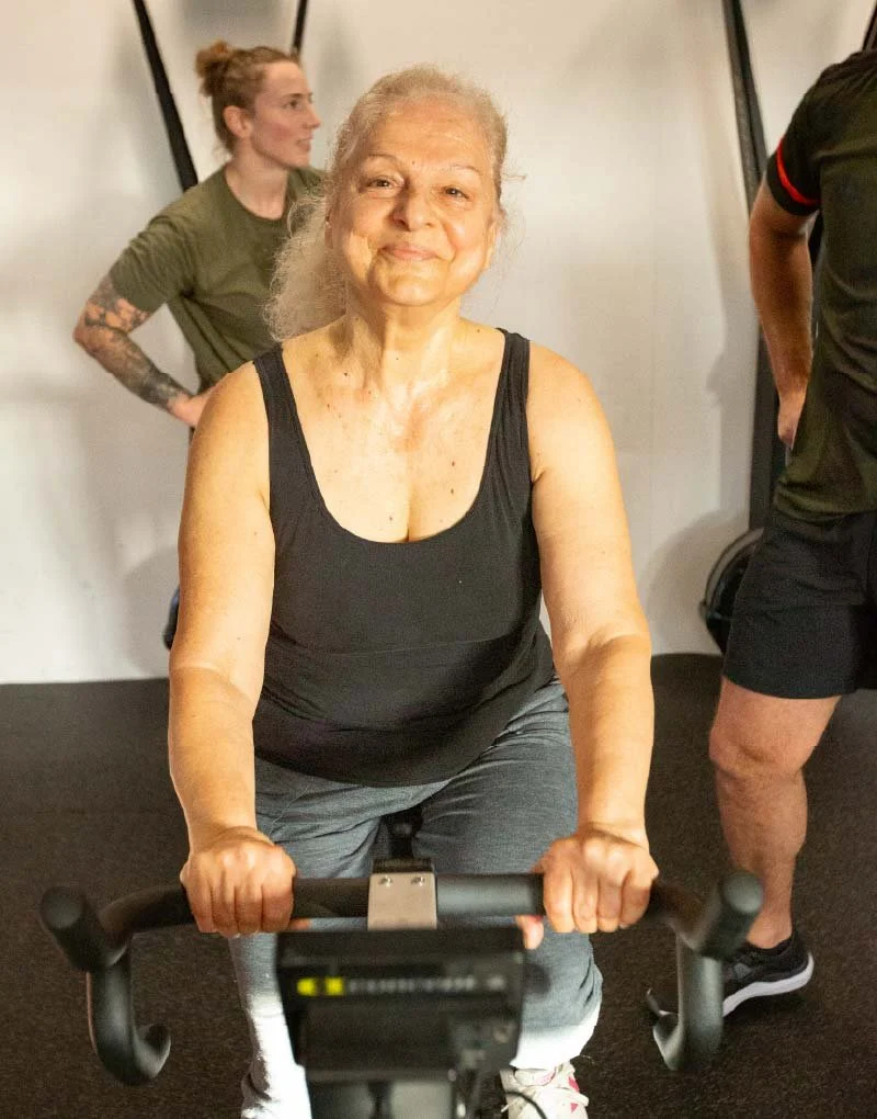 Member training on a stationary bike at BUILT Training, coached alongside others