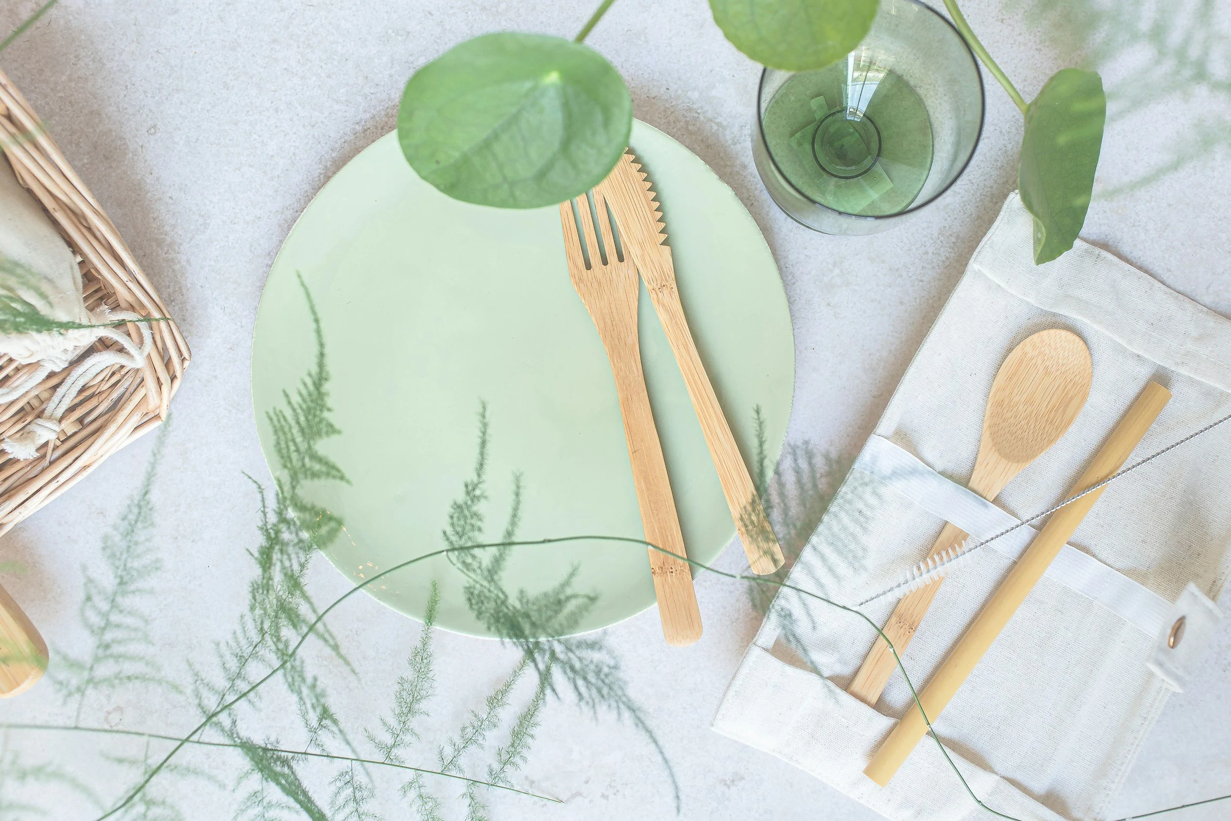 Green plate with bamboo cutlery, linen napkin and fresh greenery