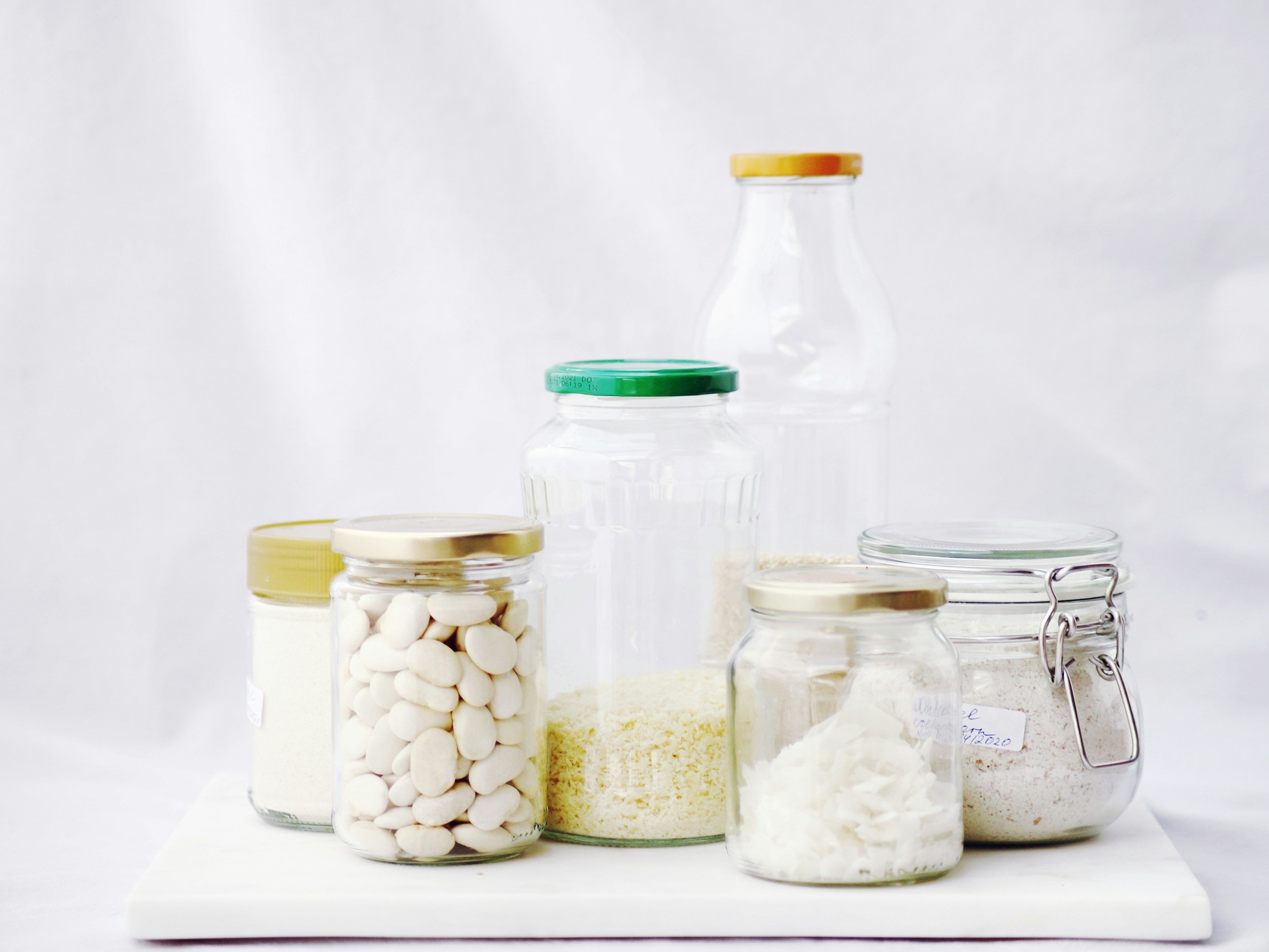 Glass jars of pantry staples on a bright white counter