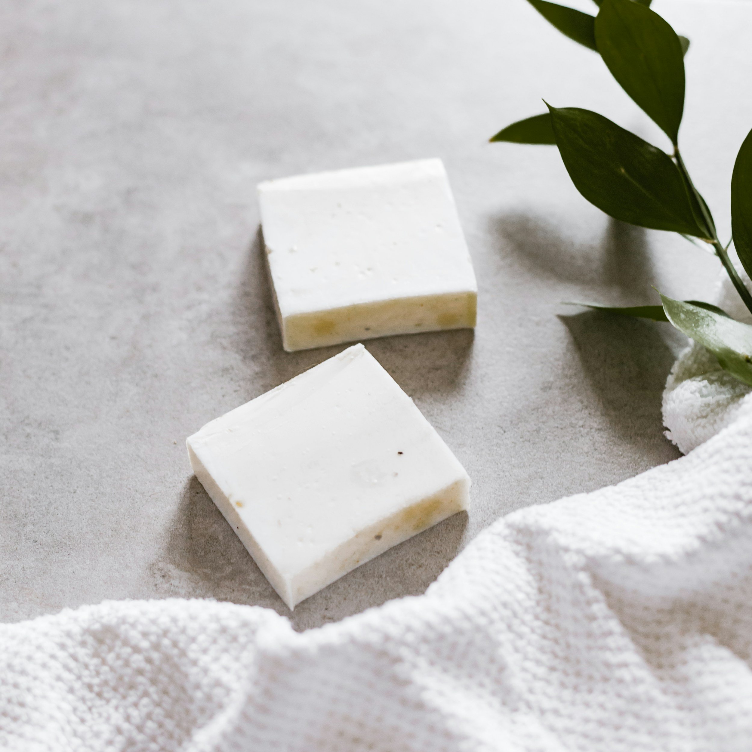 Natural white soap bars with green leaves on a soft towel