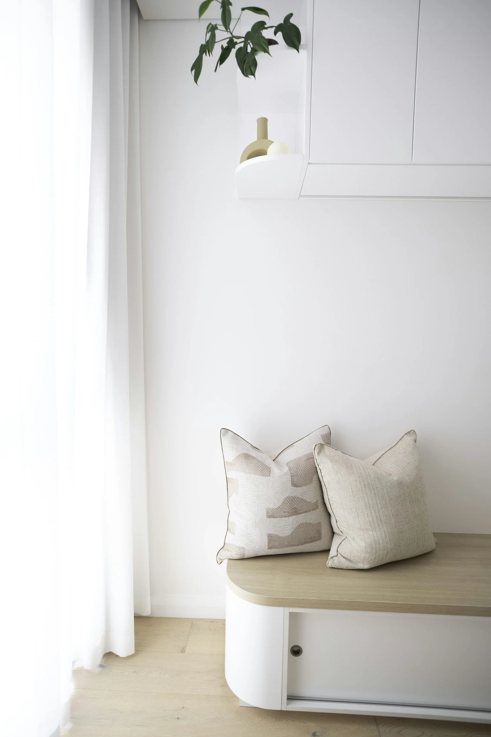 Bright room with a white bench, natural linen cushions and a green plant