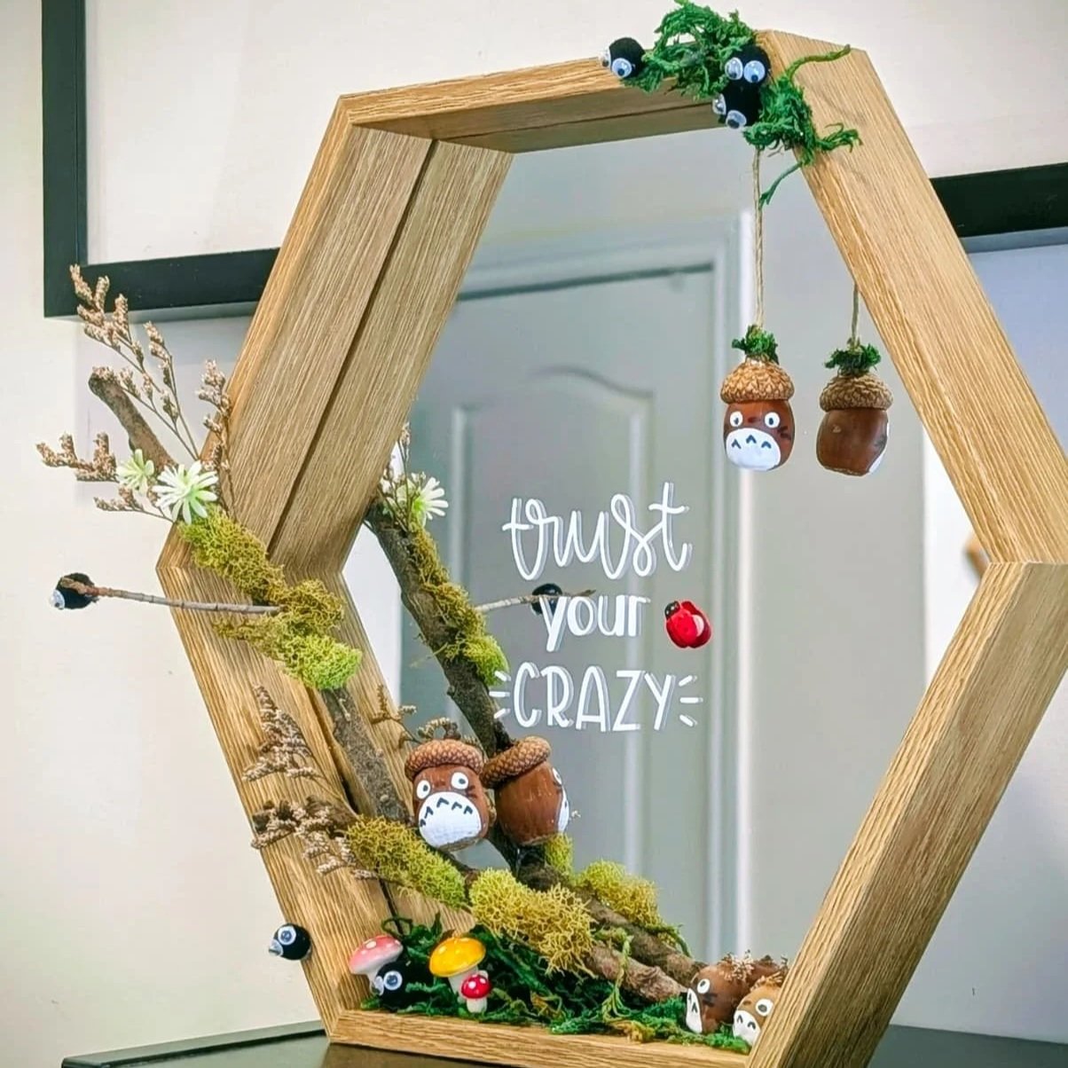 Decorative mirror with a wooden hexagonal frame, adorned with miniature mushroom and plant decorations, and a quote saying 'trust your CRAZY'.