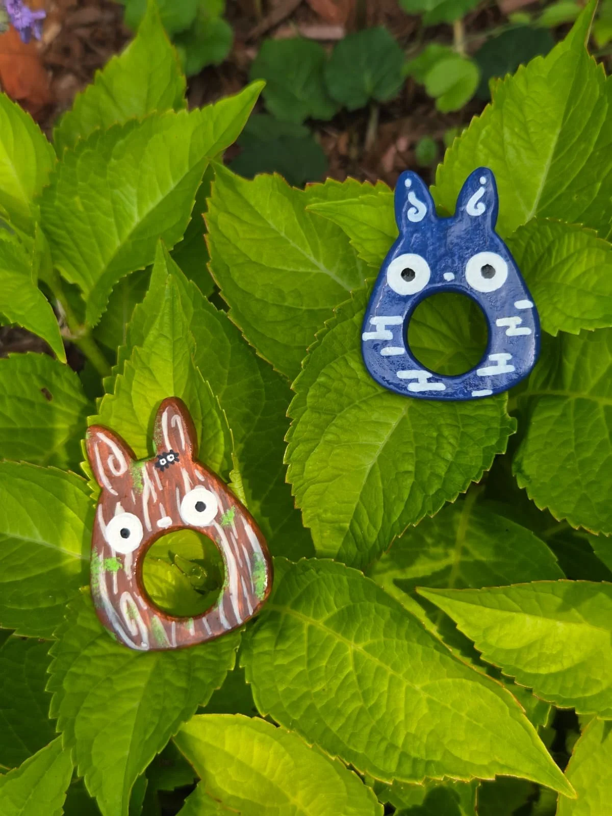 Colorful animal-shaped ceramic ornaments resembling horses on green leafy plants.