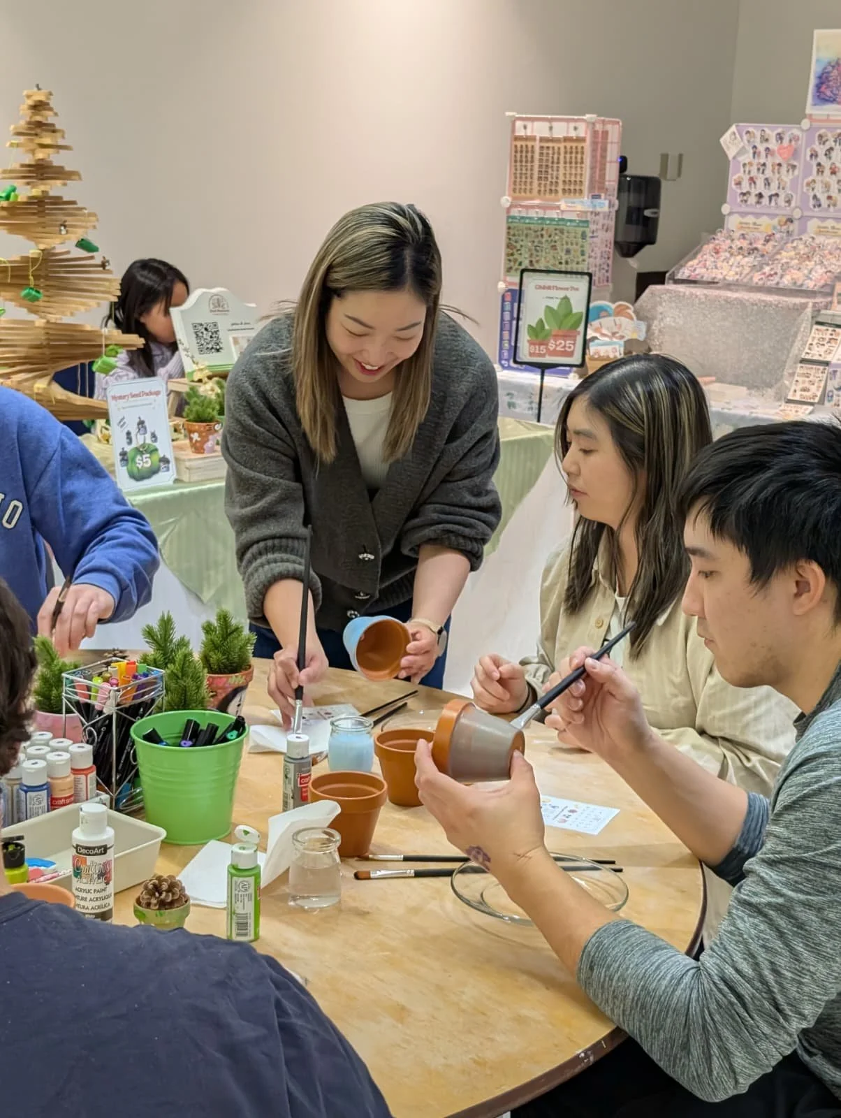 People participating in a pottery painting activity at a craft event with various craft supplies on the table.