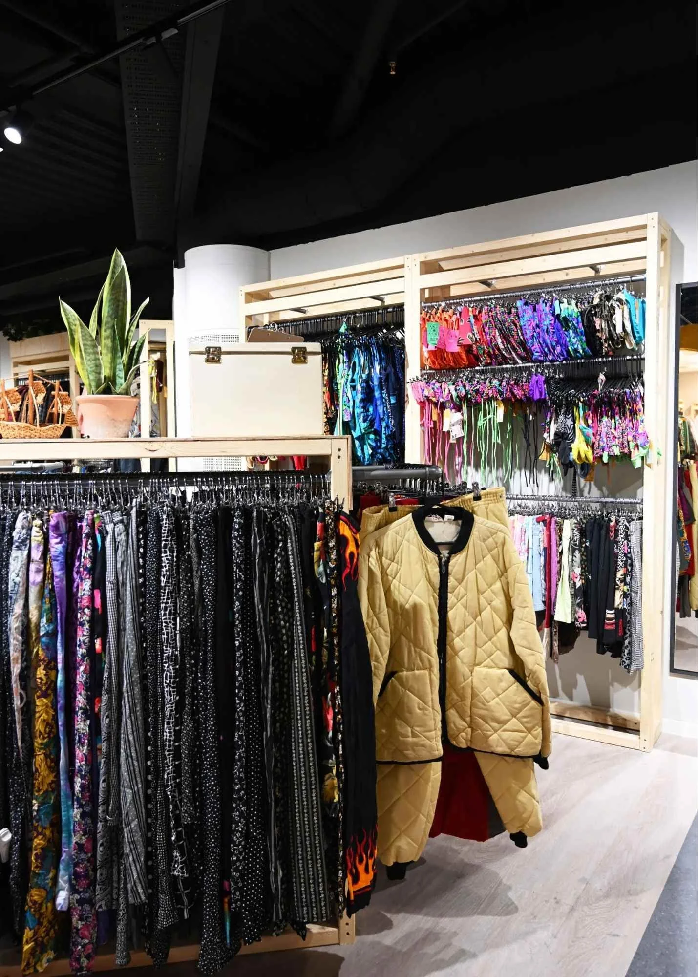 Display of colorful women's clothing, including leggings, on black hangers and racks in a retail store.