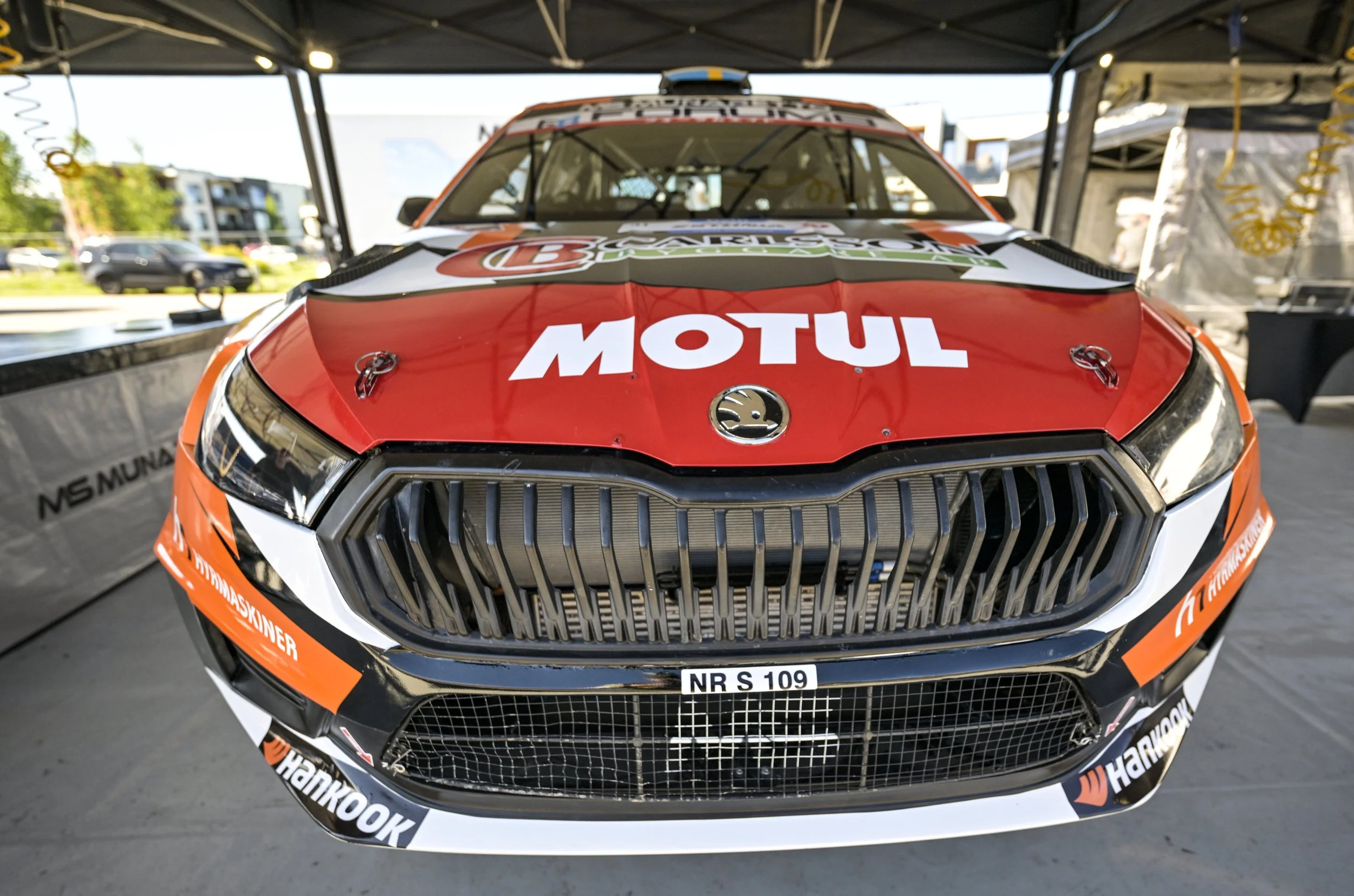 Front view of a racing car in a garage, with sponsor stickers including MOTUL and Hankook, and license plate NR S 109.