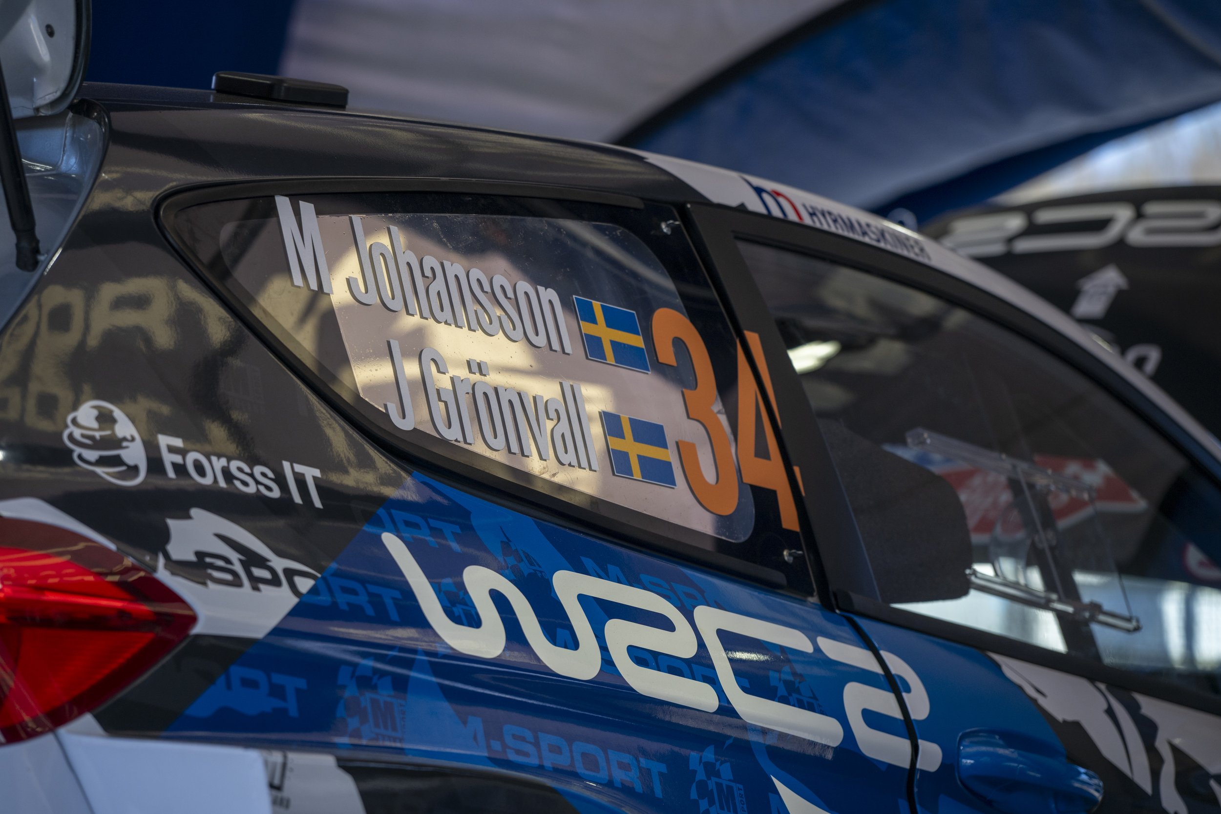 Close-up of a race car with various sponsor and driver decals, including the name J. Johansson and Swedish flags.