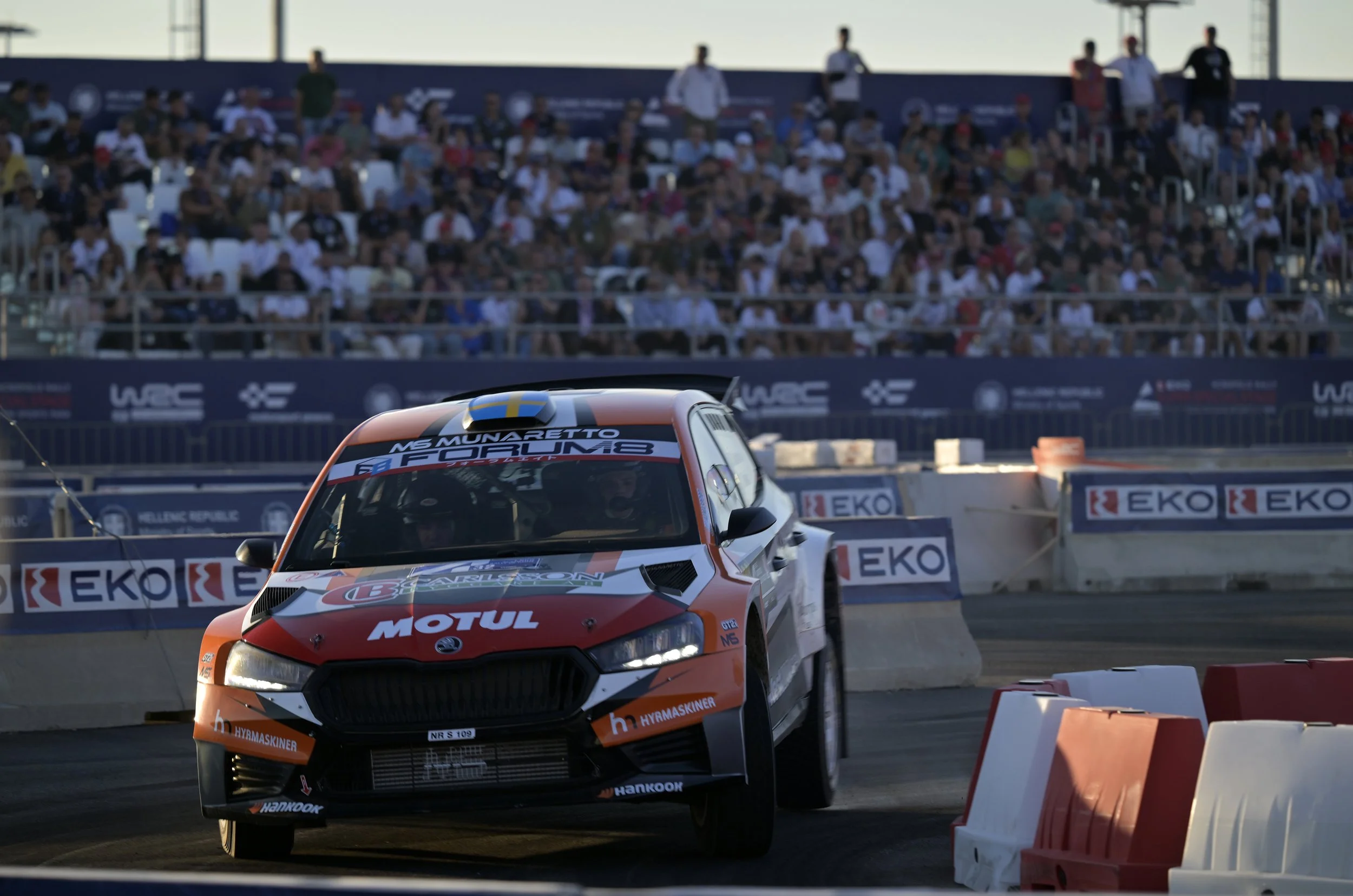 Race car on track with spectators in the background during a motorsport event.
