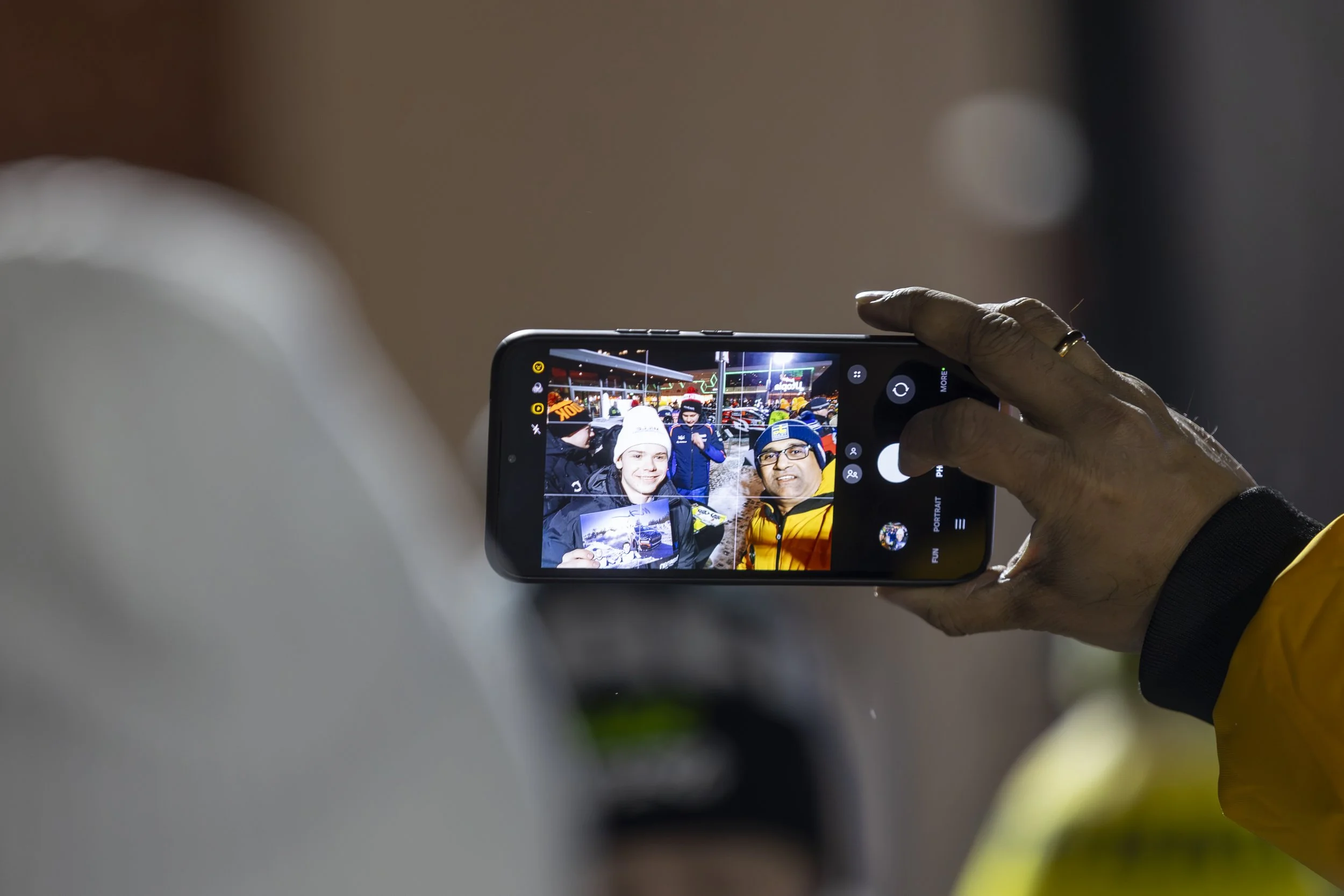 Person taking a photo on a smartphone of a group of people outdoors.