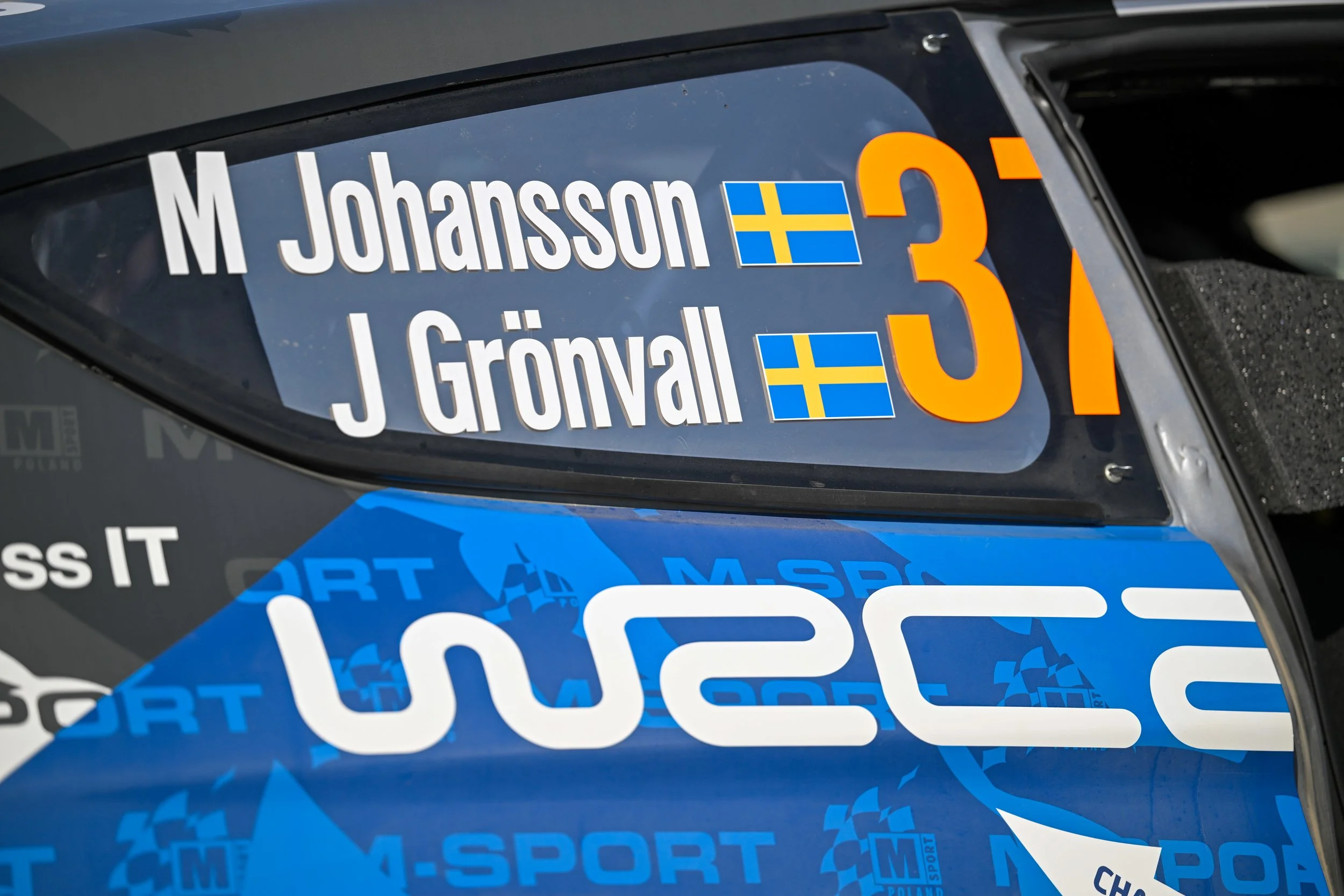 Close-up of a race car's windshield with decals including the name 'M. Johansson', Swedish flags, and the number 31.