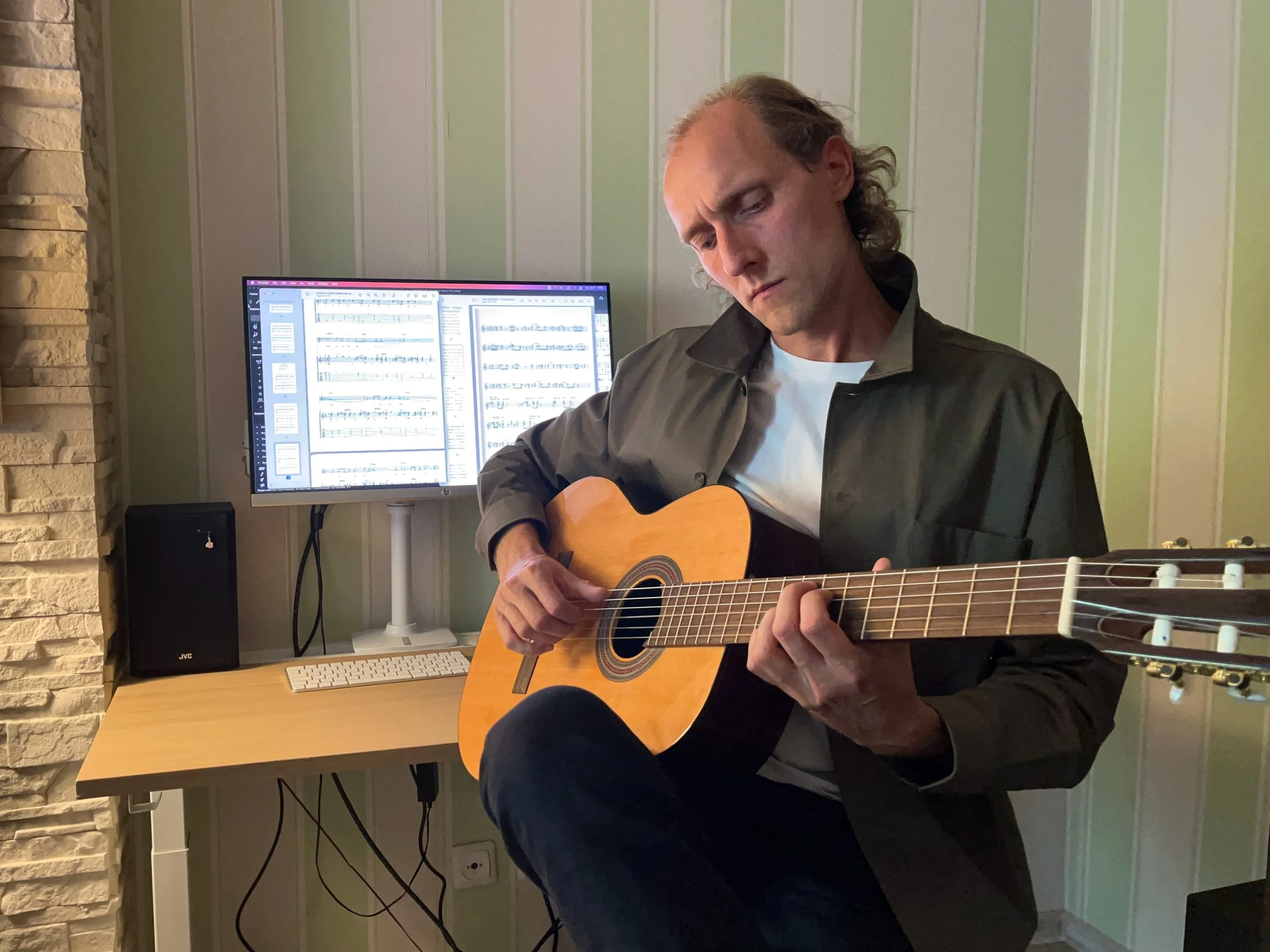 Gitaros mokytojas veda individualią klasikinės gitaros pamoką, groja nailoninių stygų gitara studijoje