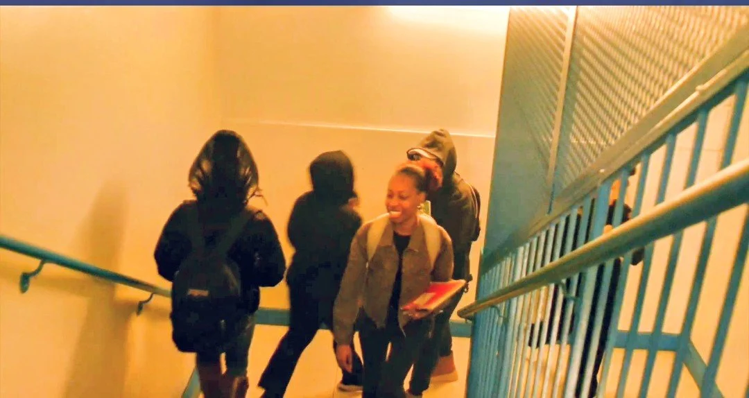Group of young people walking down a staircase, smiling and talking.