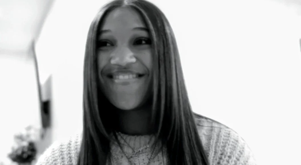 A woman with long dark hair smiling in a black and white photo.