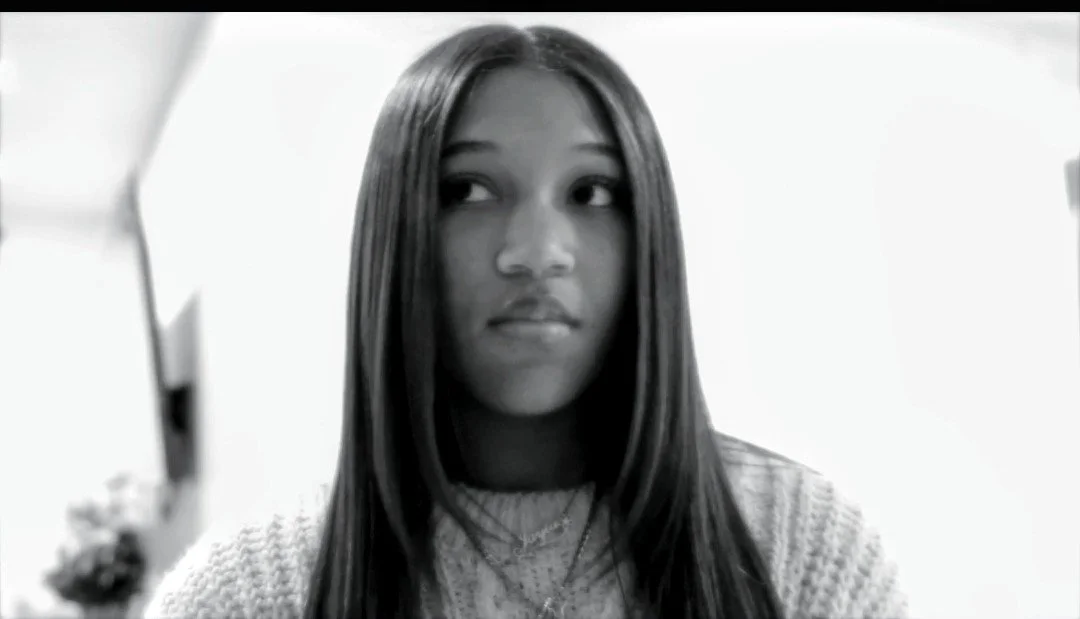 A young woman with long dark hair looking to her right, in a black and white photo.