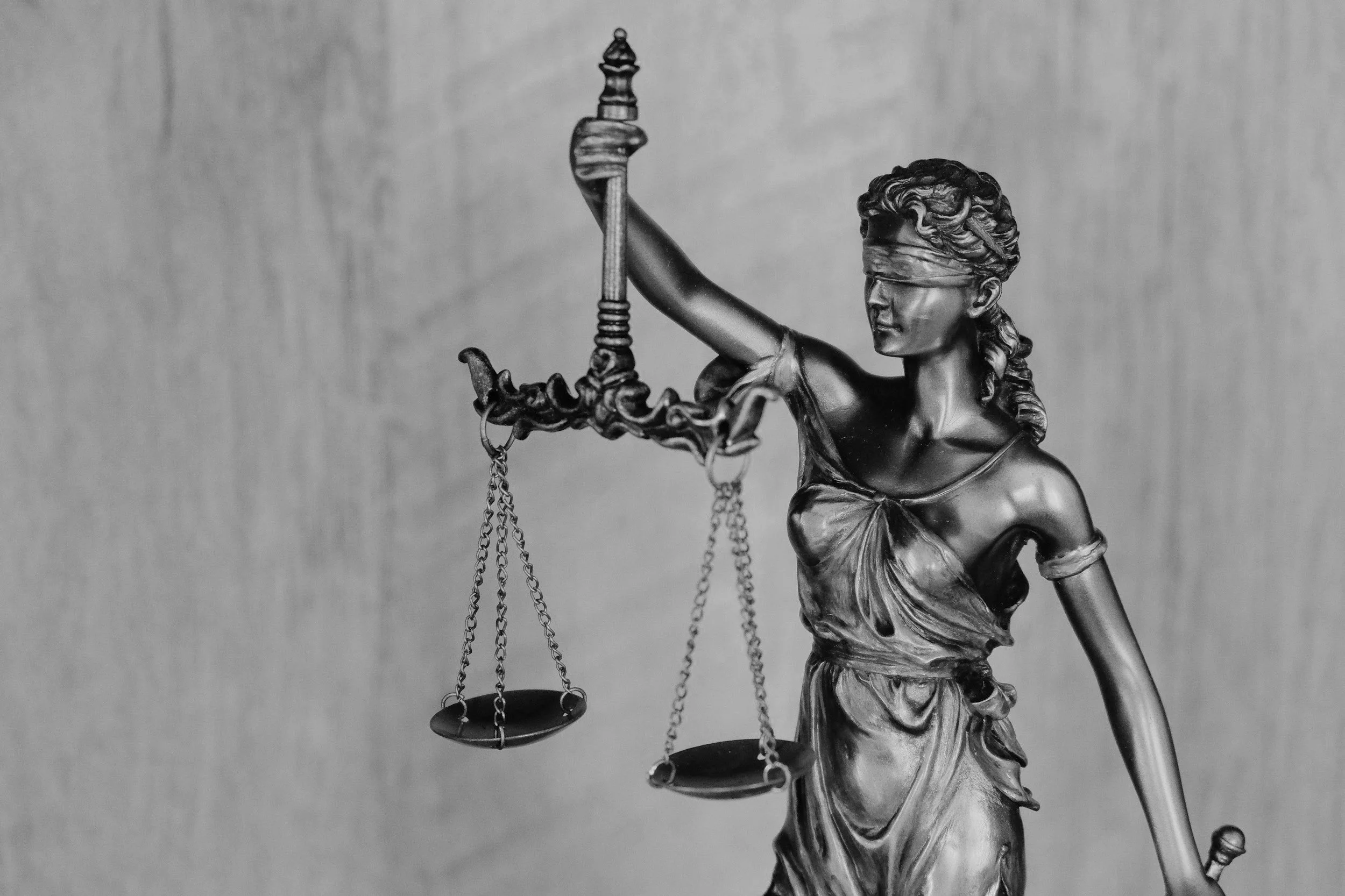 Eine Skulptur der Justitia mit verbundenen Augen, die ein Gleichgewicht auf einem Finger hält, und einer Waage in der Hand.